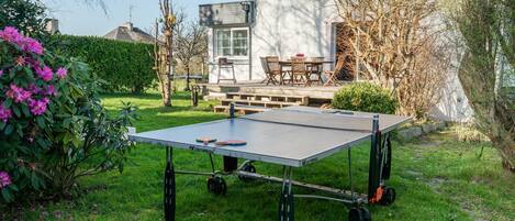 A ping pong table in a grassy area with a house in the background.