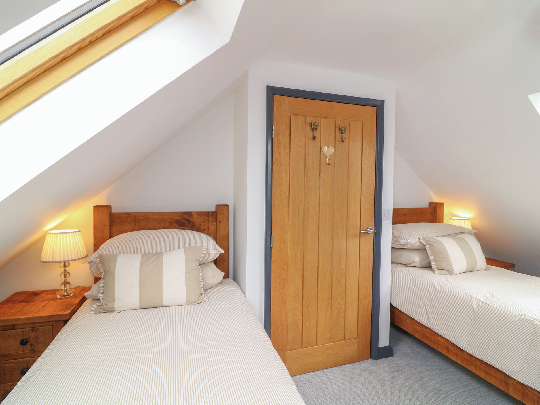 A bedroom with two beds, a wooden door, and a skylight.