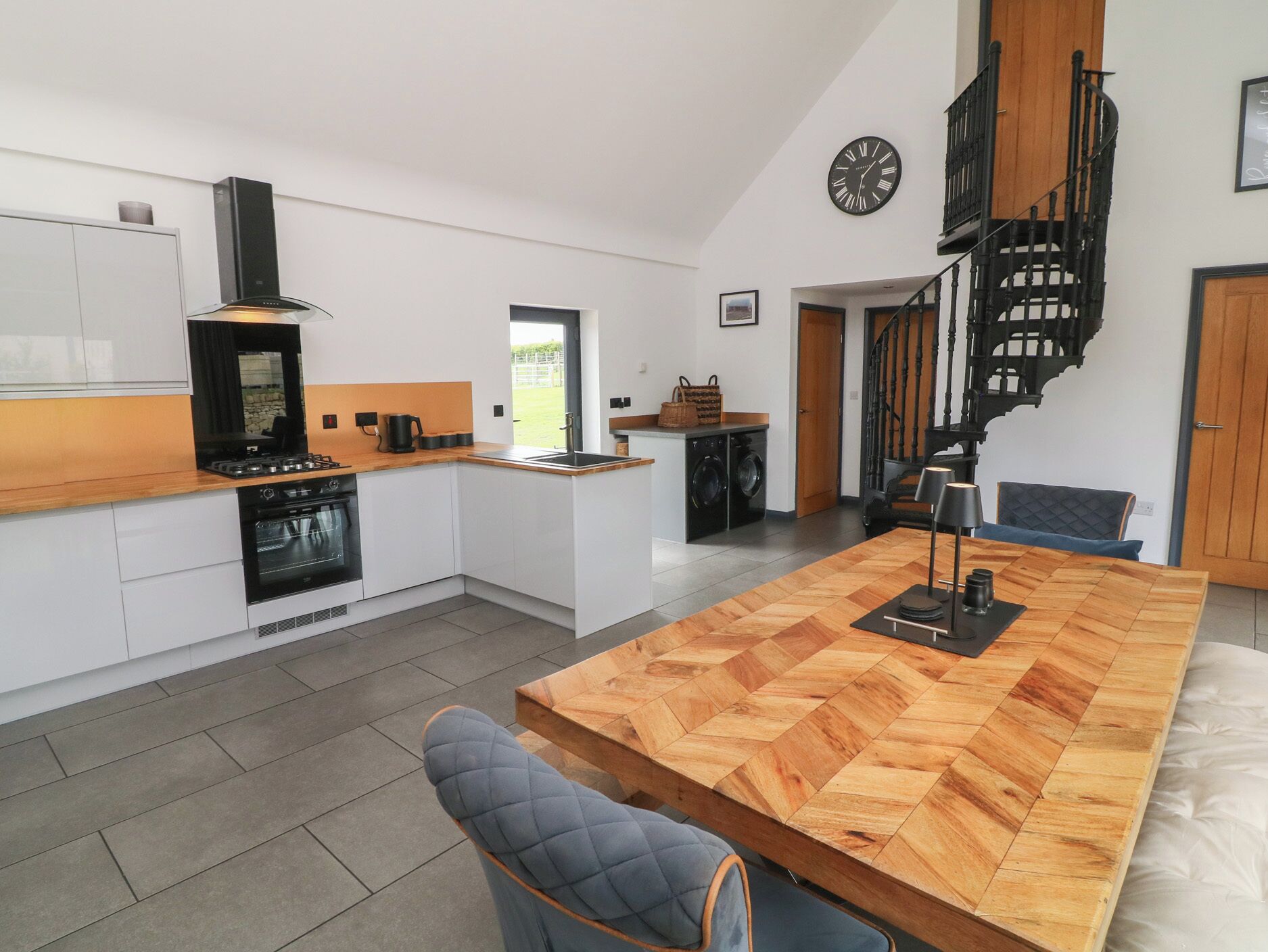 A modern kitchen with a central island, a built-in oven, and a black range hood.