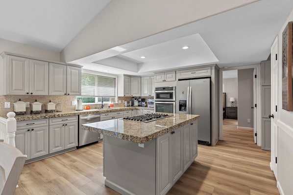 A modern kitchen with granite countertops, stainless steel appliances, and a central island. - New Listing! Spokane River Getaway | Fire Pit | Fenced Yard | Pet Friendly (Post Falls)