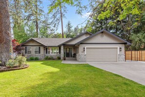 A two-story house with a garage, a front porch, and a well-maintained lawn. - New Listing! Spokane River Getaway | Fire Pit | Fenced Yard | Pet Friendly (Post Falls)