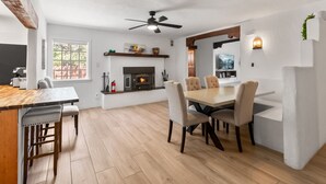 Una cocina moderna con chimenea, comedor con sillas y ventilador de techo.