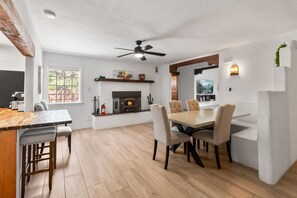 Eine moderne Küche mit Kamin, Essbereich mit Stühlen und Deckenventilator.
