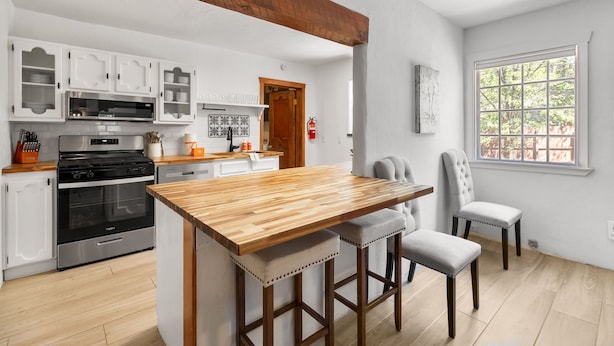 Una cocina con armarios blancos, una isla de madera y vistas al exterior a través de una ventana.