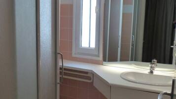 A bathroom with a sink, mirror, window, and a door.