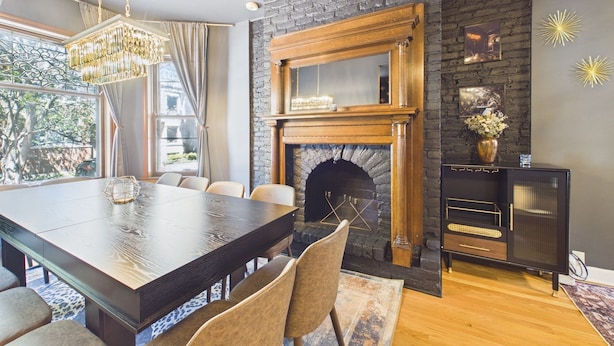 A dining area with a large table, chairs, a fireplace, and a modern chandelier. - The Dakin Estate: A refined 4BR Art Deco speakeasy duplex in Wrigleyville. Featuring curated interiors, elevated finishes, and a private entertainment lounge just minutes from Wrigley Field, dining, nightlife, and Chicago’s iconic attractions. (Chicago)