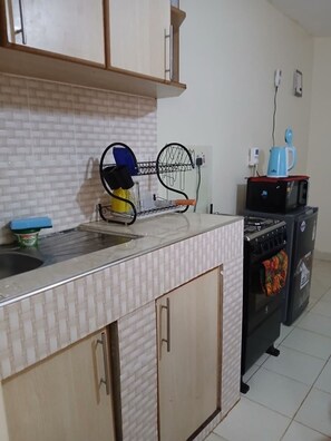 A kitchen with a tiled backsplash, a sink, a stove, and a microwave. - Beautiful and cozy odern bedroom unit in Mirema, Nairobi. 20 min drive from CBD. (Nairobi)