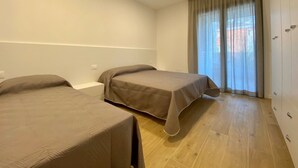 Una habitación con dos camas, una ventana con cortinas y un armario.