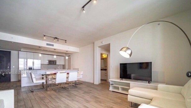 A modern living room with a sofa, TV, and dining area. - 2-bedroom apartment in Heart Of Brickell washer and dryer inside unit! (Miami)