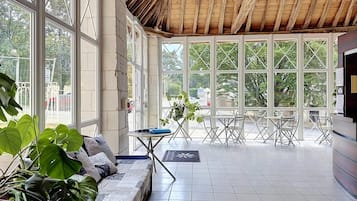Una habitació àmplia amb un sostre alt, grans finestres, un sofà i una taula petita.