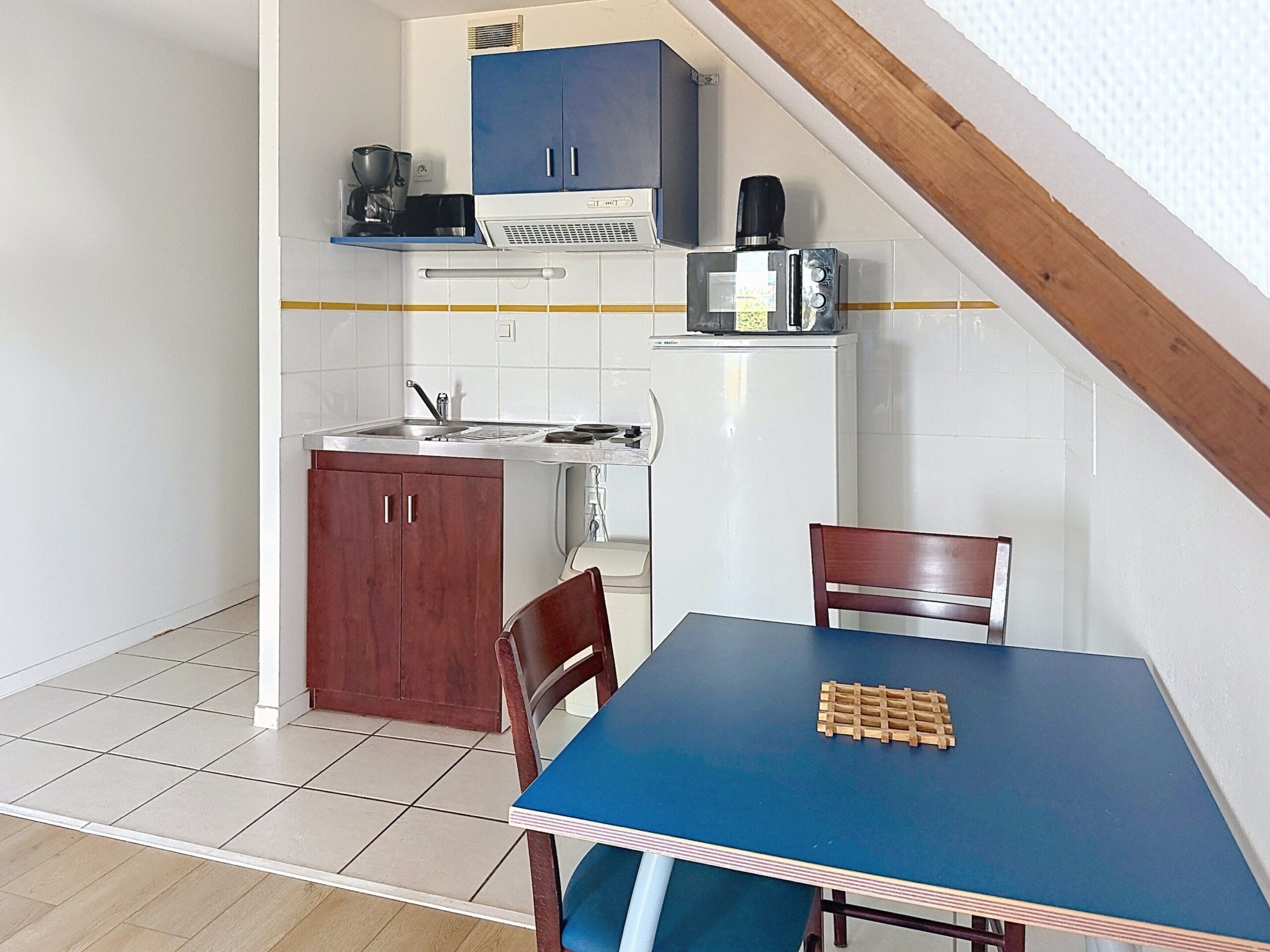 A compact kitchen with a dining table, chairs, and a coffee machine.