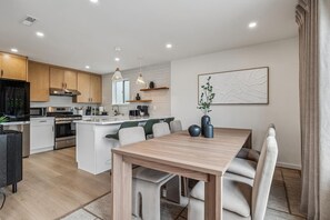 Una cocina moderna con armarios blancos, electrodomésticos de acero inoxidable y una isla central.