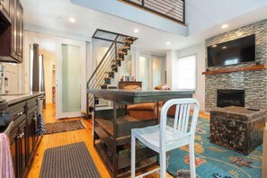 A modern kitchen with a staircase, a dining area, and a fireplace. - Chic Home w/Loft, EV Charger close to Pullman Yrds (Atlanta)