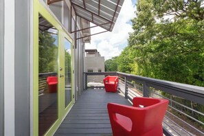 A modern balcony with glass doors, a wooden deck, and red chairs. - Chic Home w/Loft, EV Charger close to Pullman Yrds (Atlanta)