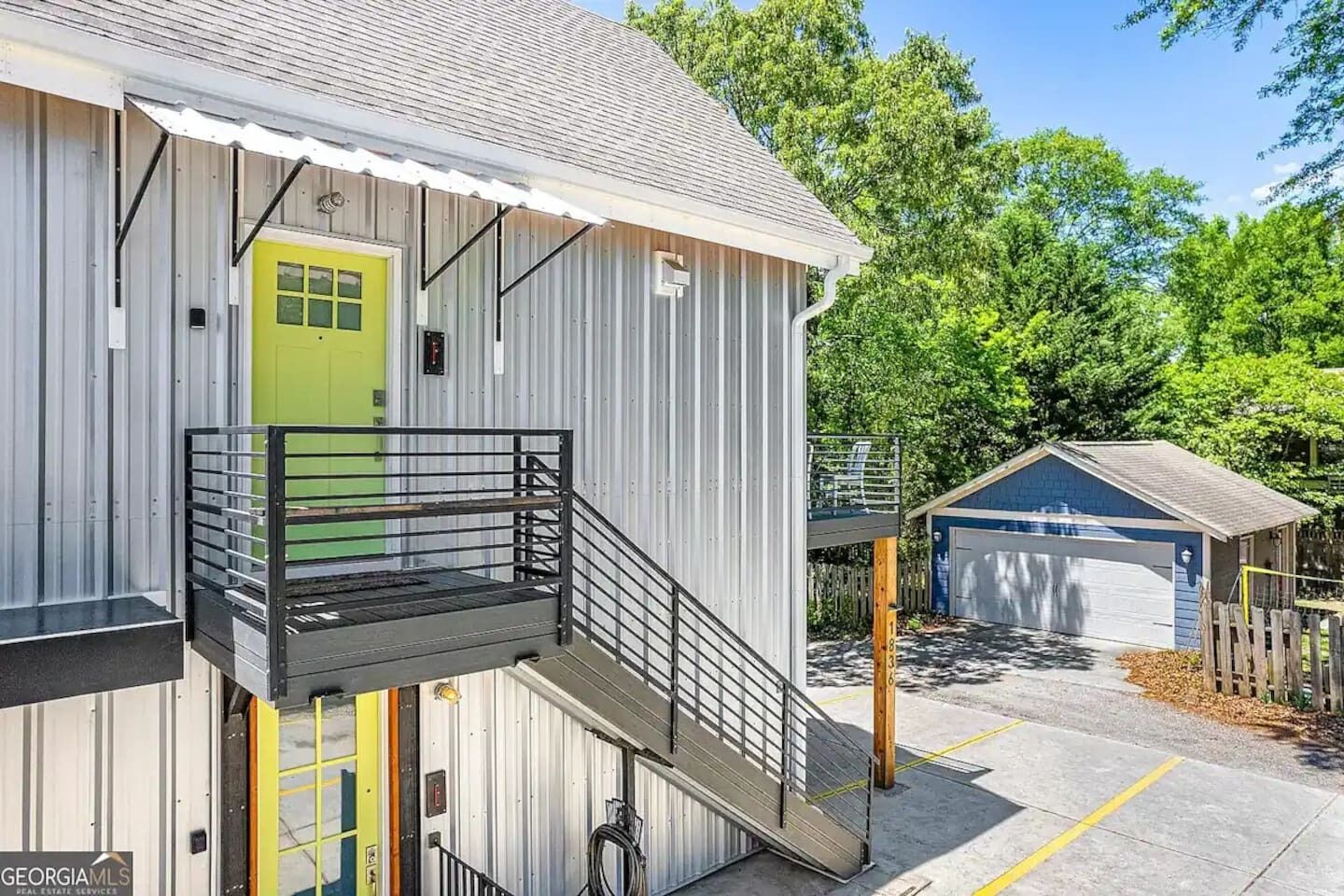 Un edificio di due piani con una porta verde, un balcone con ringhiera in metallo e un garage.