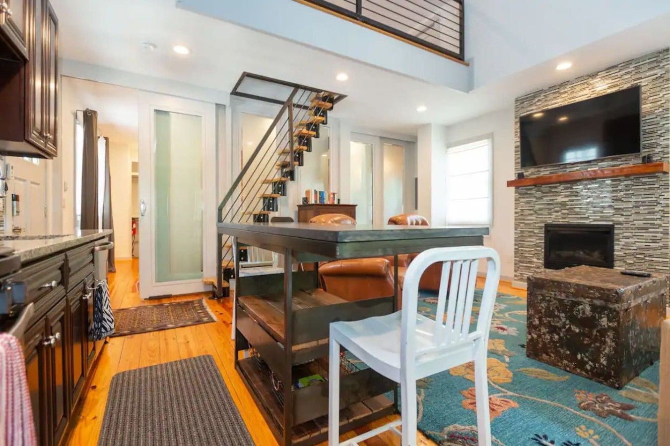 A modern interior with a kitchen, dining area, staircase, and a fireplace.