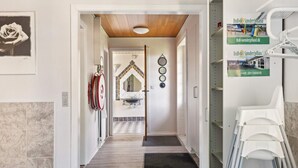 A hallway with a wooden ceiling, a mirror, a sink, and a door leading to a bathroom. - 20 Person Holiday Home in Norre Nebel (Norre Nebel)
