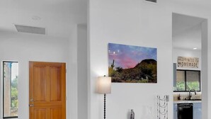 Ein modernes Interieur mit einer Holztür, einer Kommode, einer Wandleuchte und einem Landschaftsbild.