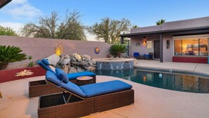 Ein Pool mit Liegestühlen, einer Whirlpool und ein Gebäude mit einer Terrasse.