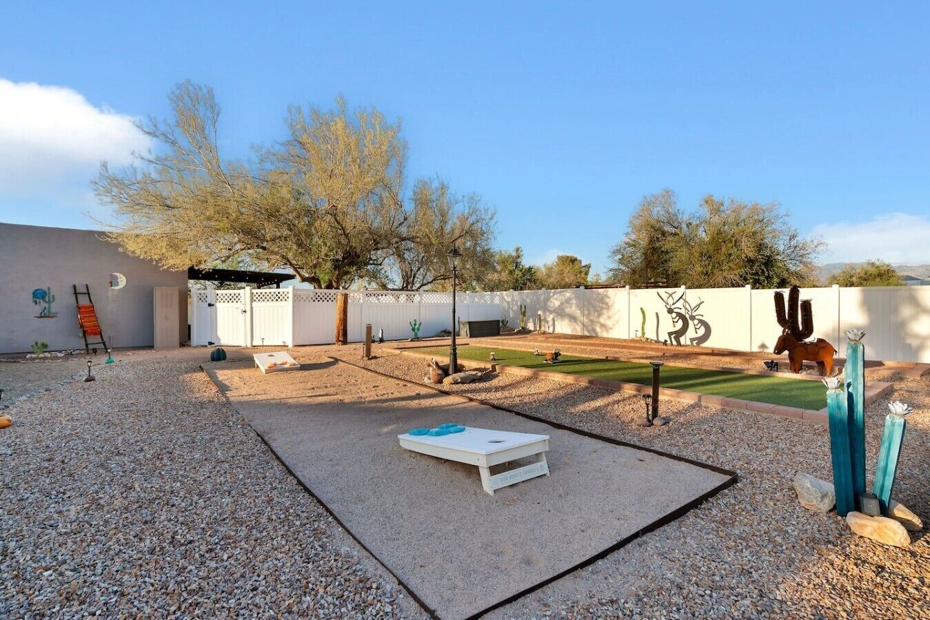 Un patio trasero con un patio, una mesa blanca y una escultura de cactus.