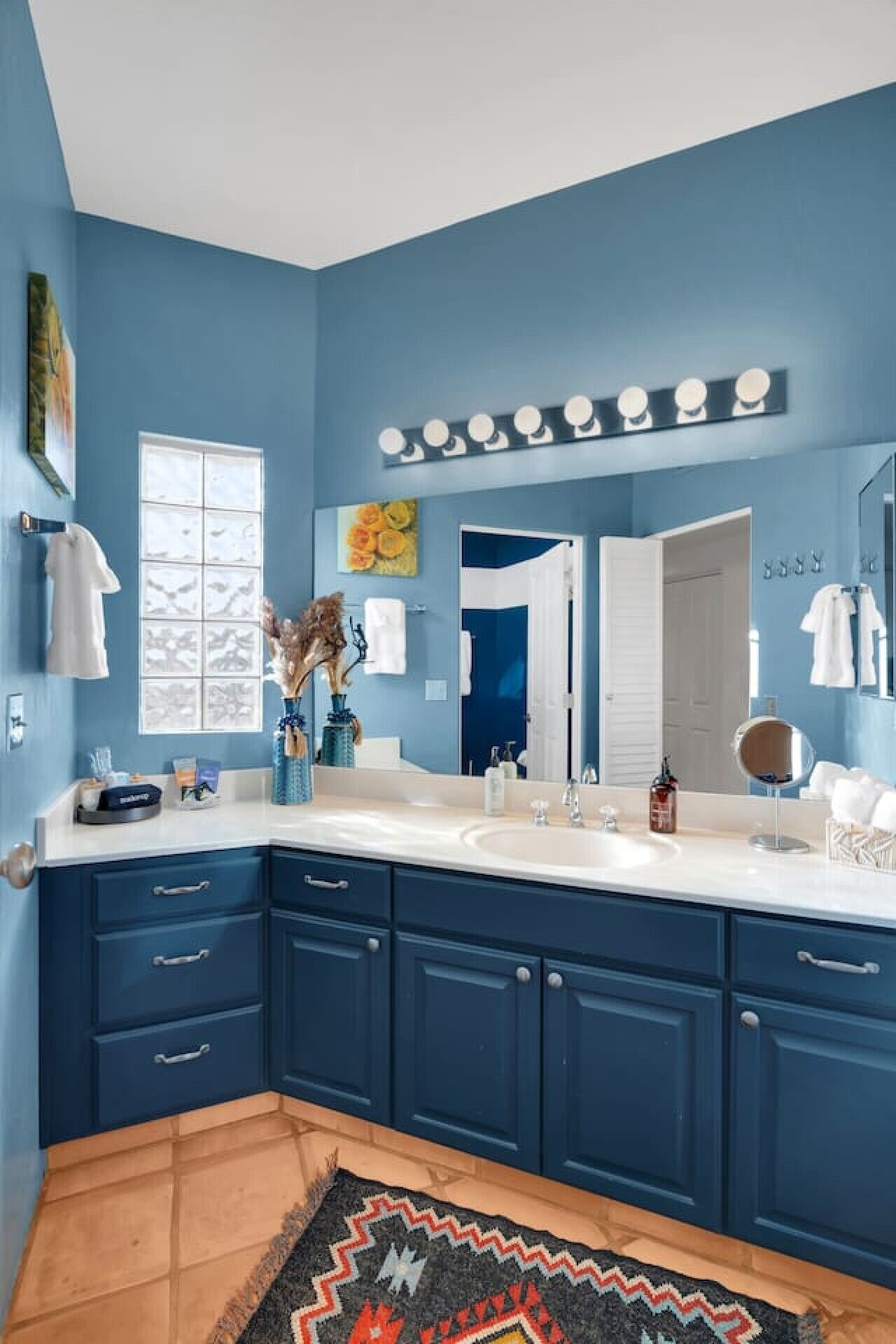 Une salle de bain avec un grand miroir, un meuble-lavabo et une fenêtre.