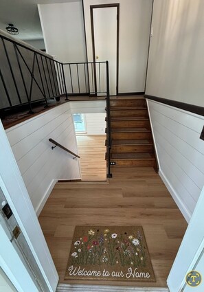 Eine Treppe mit Holzdielen und einem Metallgeländer, die zu einer Tür führt.
