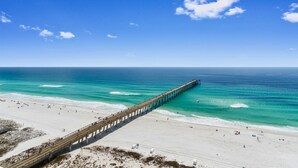 A pier extending into a beach with clear skies. - Beachfront Condo | Steps to Sand | 3 Pools (Navarre)