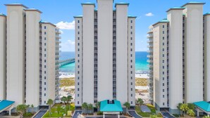 A high-rise hotel with multiple floors, a beach view, and a parking area. - Beachfront Condo | Steps to Sand | 3 Pools (Navarre)
