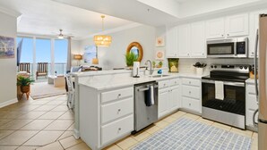 A kitchen with white cabinets, a dishwasher, a microwave, and an oven. - Beachfront Condo | Steps to Sand | 3 Pools (Navarre)