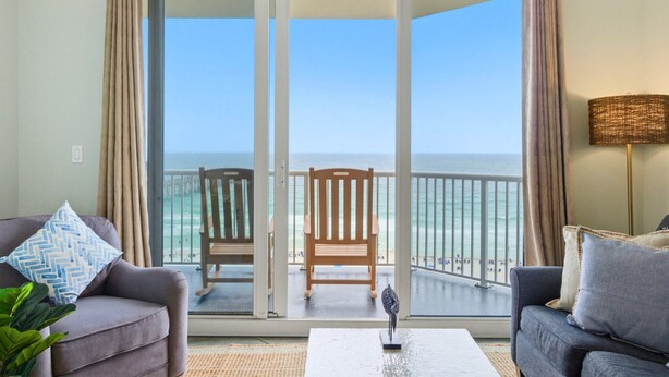 A room with a balcony, a sofa, a chair, and a lamp. - Beachfront Condo | Steps to Sand | 3 Pools (Navarre)