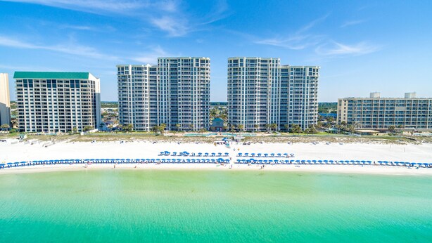 Ein Strandhotel mit mehreren Hochhäusern, einem Sandstrand und blauem Himmel.