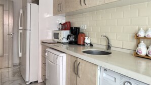 Een keuken met een vaatwasser, koffiezetapparaat, magnetron en een spoelbak.
