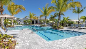 A swimming pool with lounge chairs and palm trees. - Landing Furnished Apartments - Port St. Lucie (Port Saint Lucie)