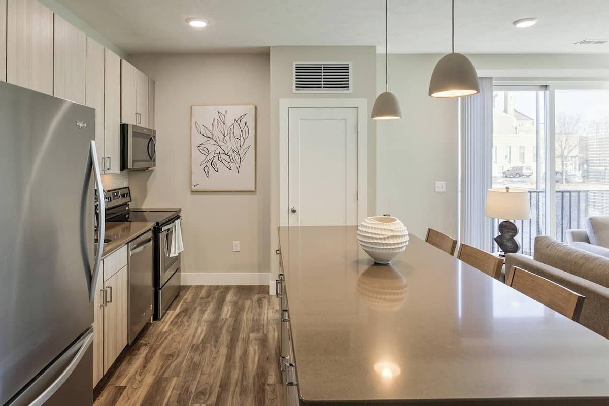 A modern kitchen with stainless steel appliances, a wooden floor, and a large island.