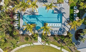 An aerial view of a resort with a central swimming pool, surrounded by palm trees and sun loungers. - Landing Furnished Apartments - Port St. Lucie (Port Saint Lucie)