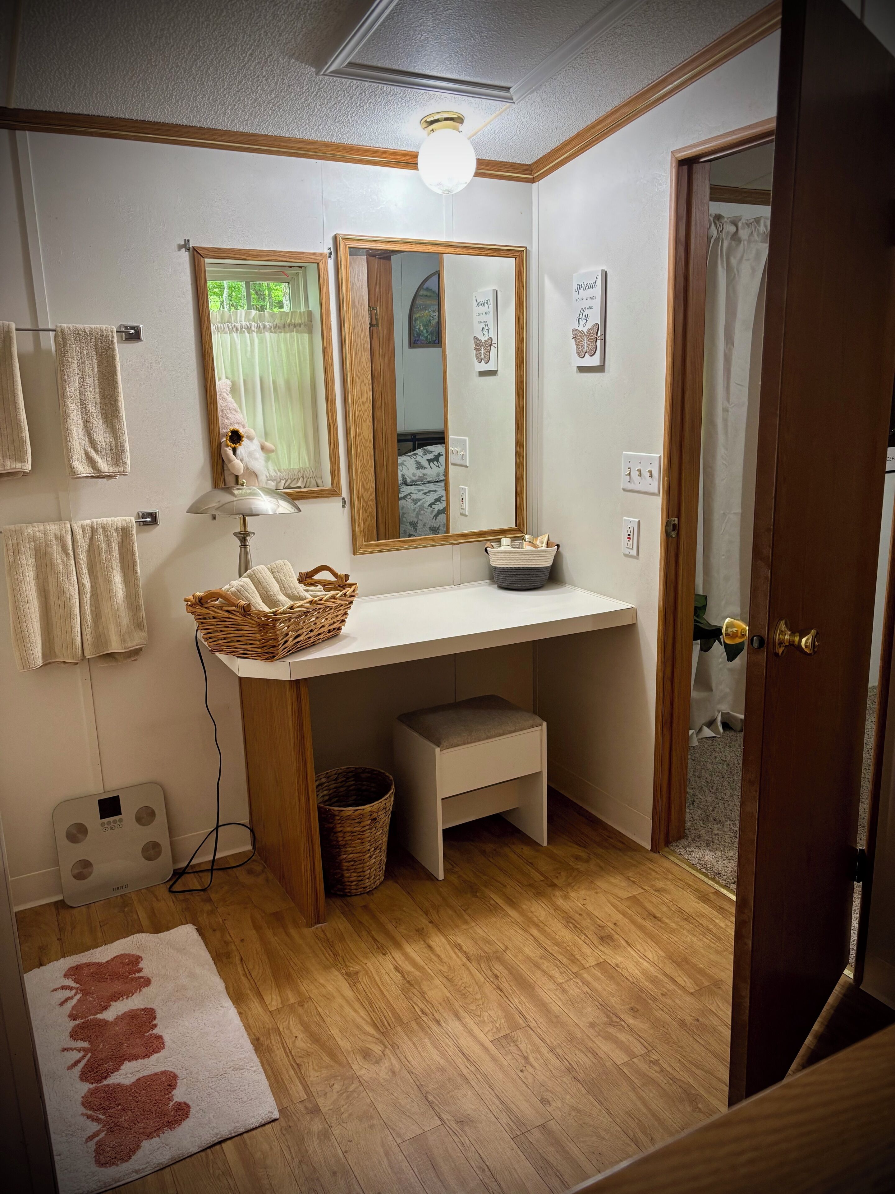A bathroom with a wooden vanity, a mirror, a towel rack, a scale, and a shower area.