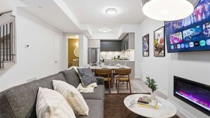 Uma sala de estar moderna com um sofá cinzento, uma mesa de centro e uma lareira.