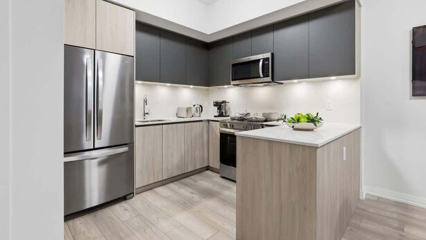 Eine moderne Küche mit Einbau-Mikrowelle, Edelstahl-Kühlschrank und Holzschränken.