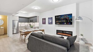 Ein modernes Wohnzimmer mit Kamin, Essbereich und einer Küche im Hintergrund.