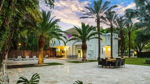 A modern house with a patio, outdoor seating, and palm trees. - Luxe Grove Villa with private pool (Miami)