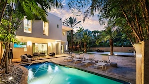 A modern house with a swimming pool, outdoor seating, and a well-maintained garden. - Luxe Grove Villa with private pool (Miami)