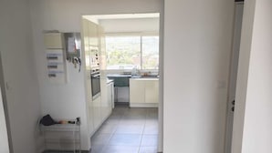 Une cuisine moderne avec une fenêtre, un coin repas avec un canapé et un couloir menant à une porte.