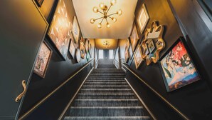 A staircase with a chandelier, framed artwork on the walls, and a carpeted floor. - The Mccaul Near Kensington Market & Chinatown (Toronto)