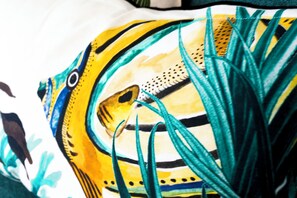 Almohada con un diseño colorido que muestra un pájaro y follaje.