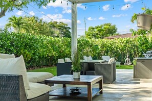 Une terrasse extérieure aménagée avec des meubles en osier, une table et des plantes en pot.