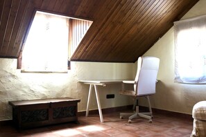 A small attic room with a sloped ceiling, a desk with a chair, a bench, and two windows. - Villa Mi Sueño | Nature | Pool & Open Skies | 3B (Málaga)