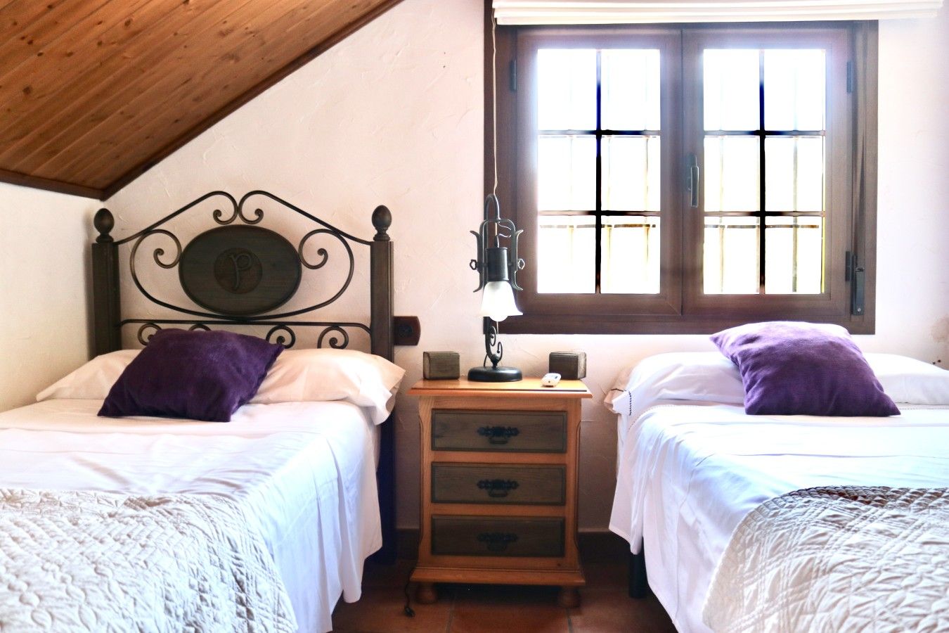 Een kamer met twee bedden, een nachtkastje, een lamp en een raam.