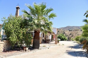 A building with a patio area, palm trees, and a mountainous backdrop. - Villa Mi Sueño | Nature | Pool & Open Skies | 3B (Málaga)
