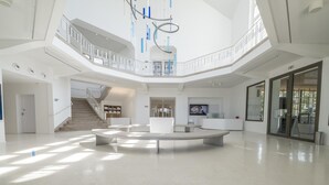 A spacious lobby with a central seating area, a staircase, and a large glass door. - Family Stay in La Roche-posay (La Roche-Posay)