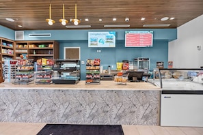 A snack bar with shelves stocked with chips and snacks, a refrigerated display case, and a menu board advertising a 'Breeze Canteen' and 'Volleyball Court'. - 10BR house with game room, sleeps 22 in clermont (Clermont)